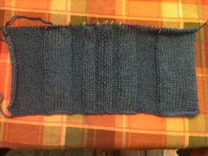 A blue-grey knitted scarf with ribs in a Fibonacci sequence, forward and backward